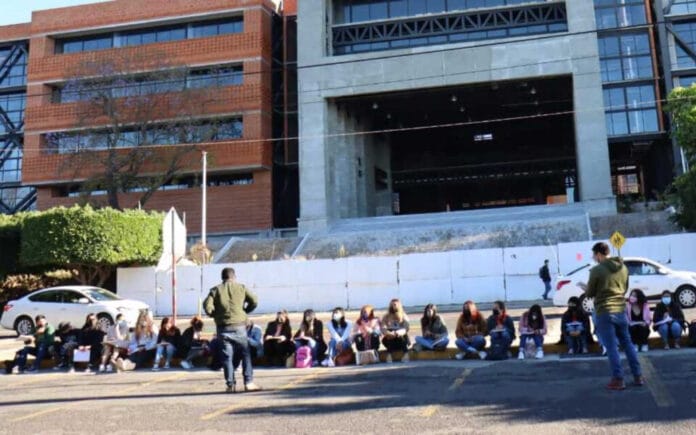 Estudiantes toman clases a las afueras de edificio